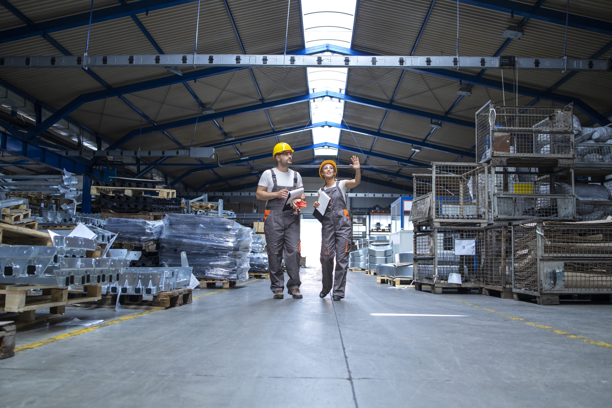 Factory workers walking through large production hall.